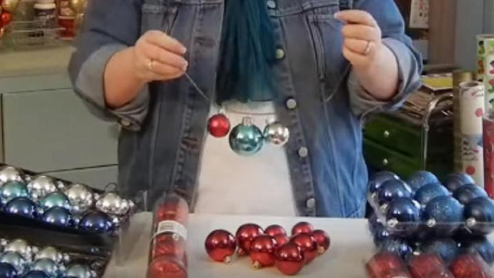 Elle enfile des boules de Noël sur un support de métal afin de créer une superbe décoration de Noël