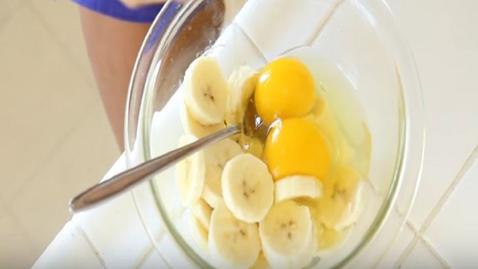 Dans un petit bol, elle casse un oeuf pour ensuite y ajouter des morceaux de banane afin de créer un déjeuner vraiment délicieux