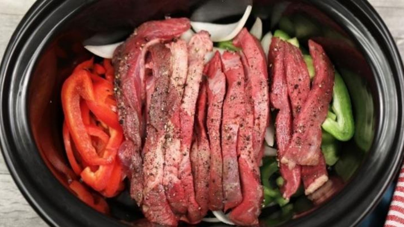 Elle met des oignons, des poivrons et des lanières de boeuf dans sa mijoteuse afin de créer le meilleur pepper steak 